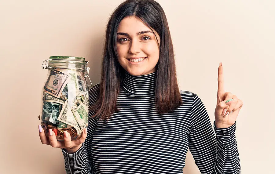 Young girl holding a jar of money